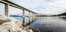 Photo: bridge crossing a fjord in a significant turn, viewed from the shore
